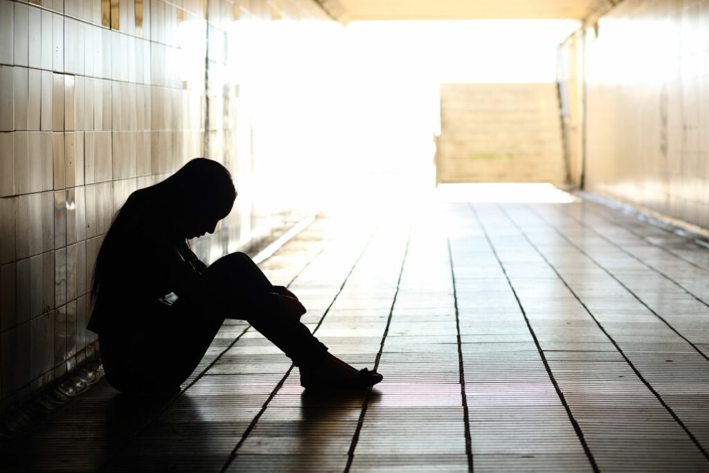 a silhouette of a man sitting on the floor, looking down