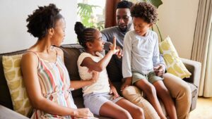 A family sitting on a couch, engaging in a lively and happy conversation, illustrating open communication and connection among family members.