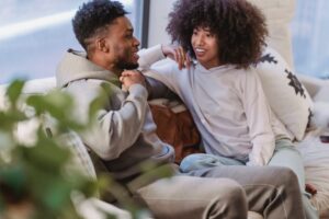 Couple sitting on a couch engaged in an open, warm conversation, practicing effective communication in their relationship.